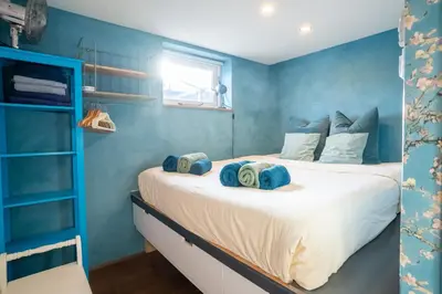 a bedroom with a large bed with blue walls at Newly renovated houseboat The Waterhouse in Amsterdam