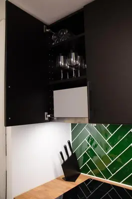 a black and white kitchen with a counter with wine glasses at Dorpsplein Appartement in Zandvoort
