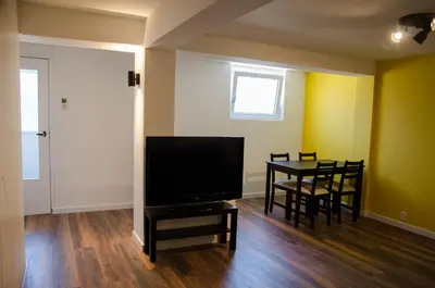 a living room with a television and a table with chairs at Dorpsplein Appartement in Zandvoort