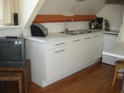 a kitchen with white cabinets and a sink and a tv at Studio Zandvoort in Zandvoort