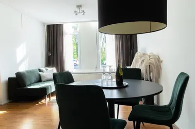 a dining room with a table and green chairs at Frankendael Apartments in Amsterdam