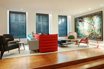 a living room with a red cabinet and chairs at citizenM Amstel Amsterdam in Amsterdam
