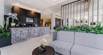 a lobby with a waiting area with plants at PLAZA Premium Almere in Almere