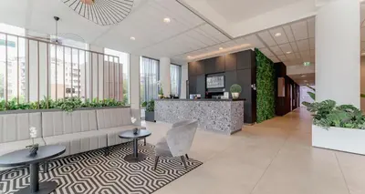 an office lobby with a couch and tables and plants at PLAZA Premium Almere in Almere