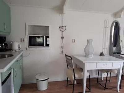 a kitchen with a white table and a microwave at Rietzicht in Alkmaar