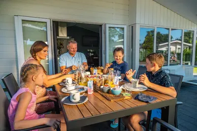 a family sitting at a table eating food at EuroParcs Parc du Soleil in Noordwijk aan Zee