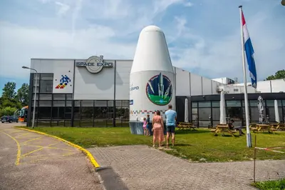 a group of people standing in front of a building with a space shuttle at EuroParcs Parc du Soleil in Noordwijk aan Zee
