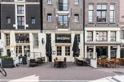 a restaurant with tables and umbrellas in front of a building at Anny's Warehouse City Centre! in Amsterdam