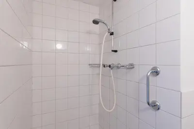 a white tiled shower with a shower head at Anny's Warehouse City Centre! in Amsterdam