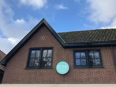 a brick house with two windows and a sign on it at ECHT-Bergen in Bergen