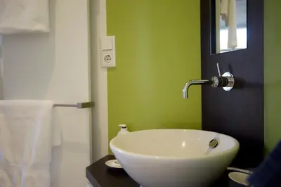 a white sink in a bathroom with green walls at B&B Muntzicht in Utrecht