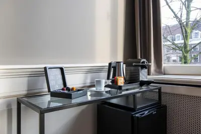 a glass desk with a laptop computer on top of it at Grand Canal Boutique Hotel in Amsterdam
