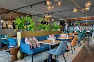 a restaurant with blue couches and tables and plants at Renaissance Amsterdam Schiphol Airport Hotel in Schiphol