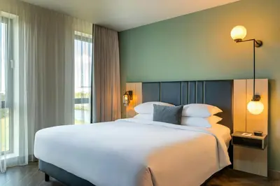 a bedroom with a large white bed and a large window at Renaissance Amsterdam Schiphol Airport Hotel in Schiphol