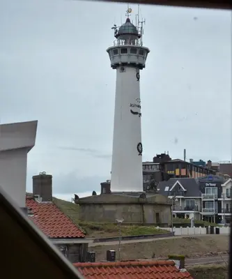 a lighthouse in the middle of a town with houses at Appartementen Dorp & Duin in Egmond aan Zee