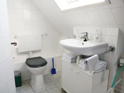 a white bathroom with a toilet and a sink at Appartementen Dorp & Duin in Egmond aan Zee