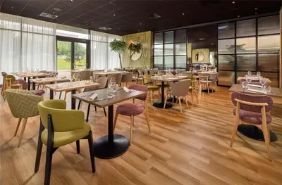 a restaurant with wooden floors and tables and chairs at Hilton Garden Inn Leiden in Leiden