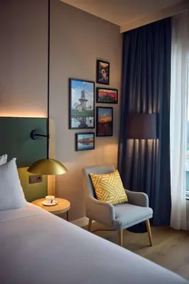 a bedroom with a bed and a chair and a lamp at Hilton Garden Inn Leiden in Leiden