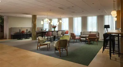 a lobby with chairs and a table and a dining room at Hilton Garden Inn Leiden in Leiden