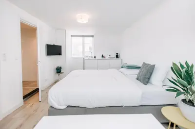 a white bedroom with a white bed and a tv at Zylt Zandvoort in Zandvoort