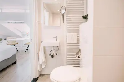 a white bathroom with a toilet and a sink at Zylt Zandvoort in Zandvoort