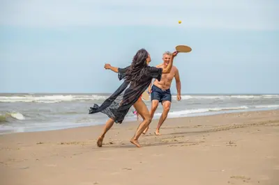 a man and woman playing frisbee on the beach at EuroParcs Noordwijkse Duinen in Noordwijk aan Zee