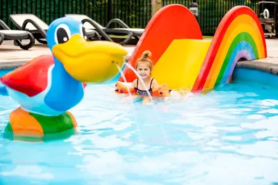 a little girl playing on an inflatable duck in a pool at EuroParcs Noordwijkse Duinen in Noordwijk aan Zee