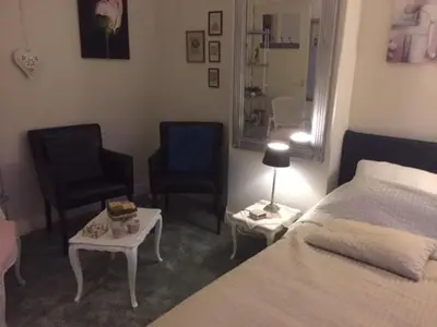 a bedroom with a bed and two chairs and a table at Gezellige zolder in Wassenaar met dakterras in Wassenaar
