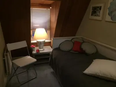 a bedroom with a bed and a chair and a lamp at Gezellige zolder in Wassenaar met dakterras in Wassenaar