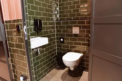 a bathroom with a toilet and green tiled walls at Durty Nelly's Inn in Amsterdam