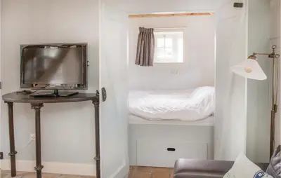 a living room with a television and a bed at Het Vissershuisje in Wijdenes