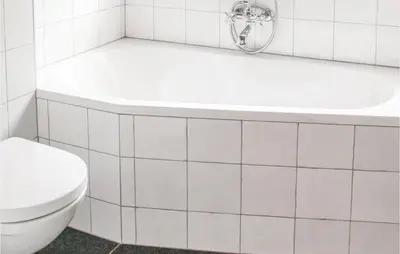 a white bathroom with a toilet and a bath tub at Het Vissershuisje in Wijdenes