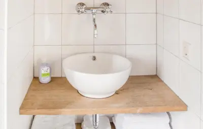 a bathroom with a white bowl sink on a wooden counter at Het Vissershuisje in Wijdenes