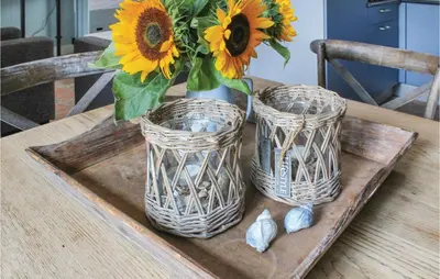three wicker vases sitting on a wooden table with a bouquet of flowers at Het Vissershuisje in Wijdenes