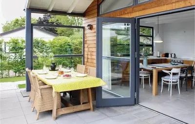 a dining room with sliding glass doors and a table at Das Sommerhus 68 in Noordwijk aan Zee