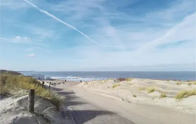 a dirt road leading to a beach with the ocean at Das Sommerhus 68 in Noordwijk aan Zee