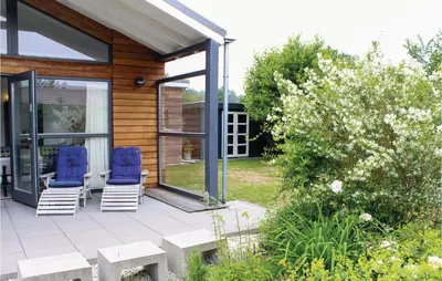 two blue chairs sitting on a patio next to a house at Das Sommerhus 68 in Noordwijk aan Zee