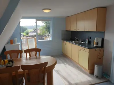 a kitchen with a wooden table and a dining room at Appartement Soigner! in Egmond-Binnen