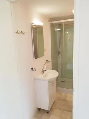 a white bathroom with a sink and a shower at Appartement Soigner! in Egmond-Binnen