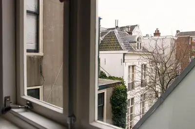 an open window with a view of buildings at Amsterdam Canal Suites in Amsterdam