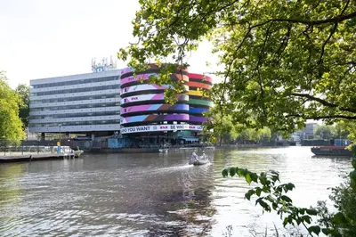 a boat on a river in front of a building at Nassau Canal Suites - in the heart of the city in Amsterdam