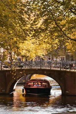 a boat traveling down a river under a bridge at Nassau Canal Suites - in the heart of the city in Amsterdam
