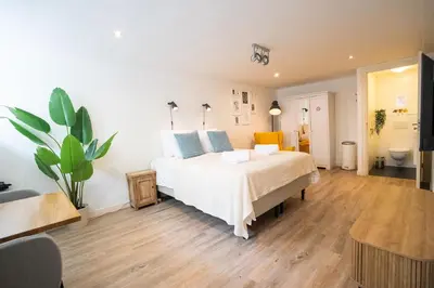 a bedroom with a large white bed with blue pillows at Nassau Canal Suites - in the heart of the city in Amsterdam