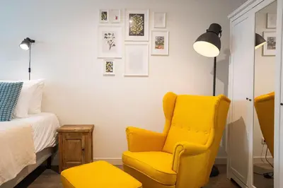 a bedroom with a yellow chair and a bed at Nassau Canal Suites - in the heart of the city in Amsterdam