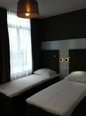 two beds in a room with a window at Hotel Vossius Vondelpark in Amsterdam