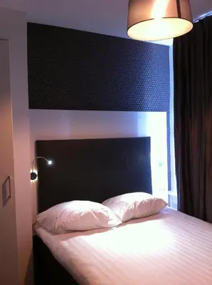 a bedroom with a large bed with a black headboard at Hotel Vossius Vondelpark in Amsterdam