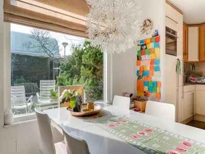 a dining room with a white table and a chandelier at Holiday Home Noordwijk near Beach & Sauna in Noordwijk