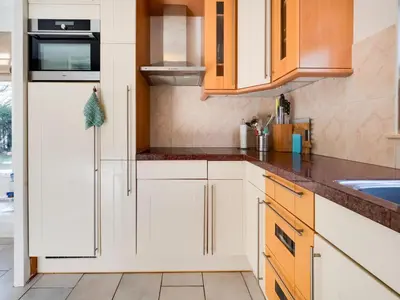 a kitchen with white cabinets and a sink at Holiday Home Noordwijk near Beach & Sauna in Noordwijk