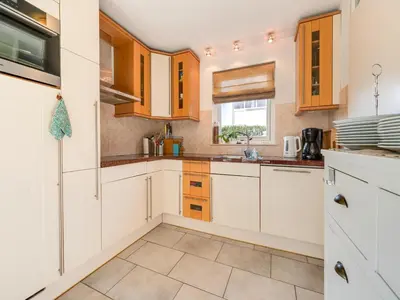 a kitchen with white cabinets and a window at Holiday Home Noordwijk near Beach & Sauna in Noordwijk