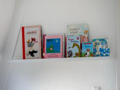 a shelf with books on top of a wall at Holiday Home Noordwijk near Beach & Sauna in Noordwijk